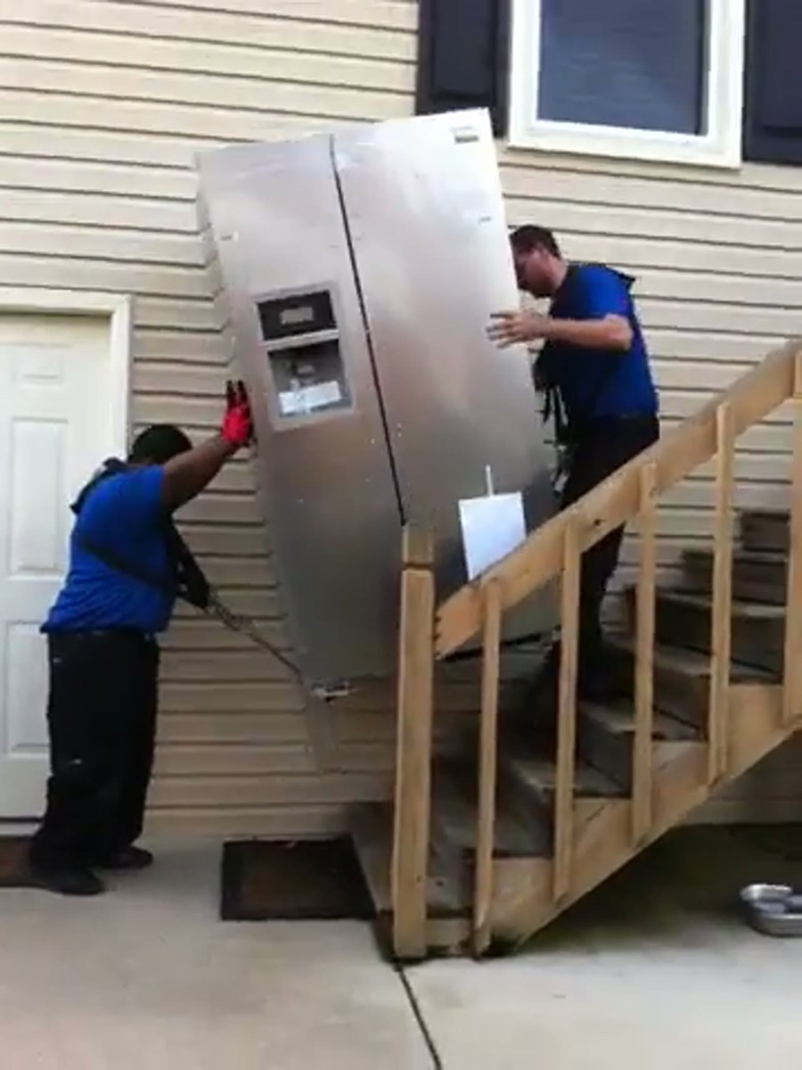 An Up and Coming crew carrying a wrapped piece into a Lexington home